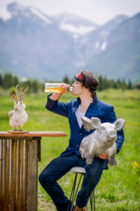 A man drinking orange color juice with a silver pig idol