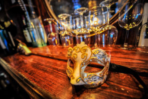 A mask on the bar with wine glasses